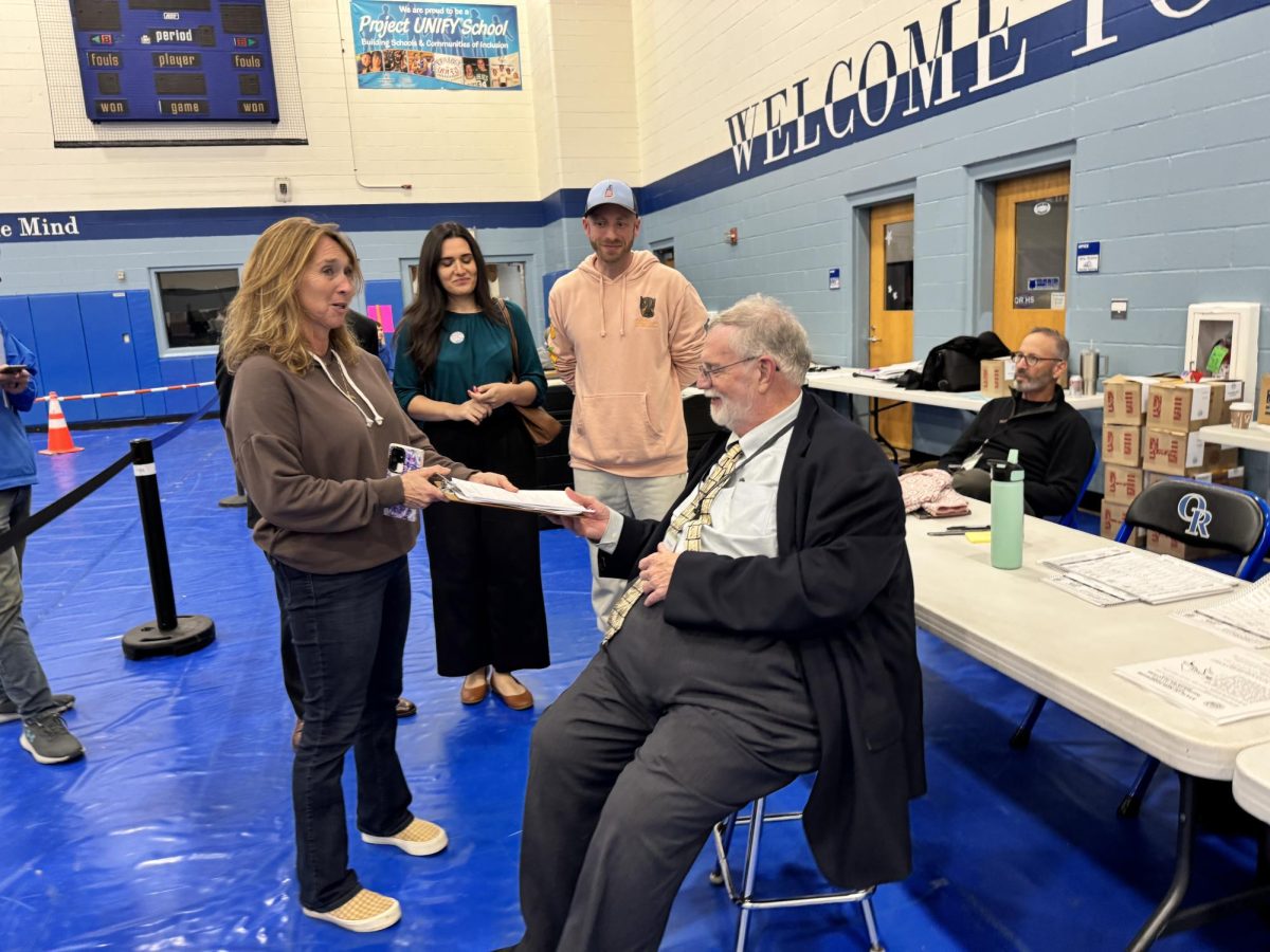 Election moderator Chris Regan (center right) and Town Administrator Todd Selig (far right) discuss the group’s challenge submission, while Brenda Towne (left) waits off to the side challenge submission in hand.